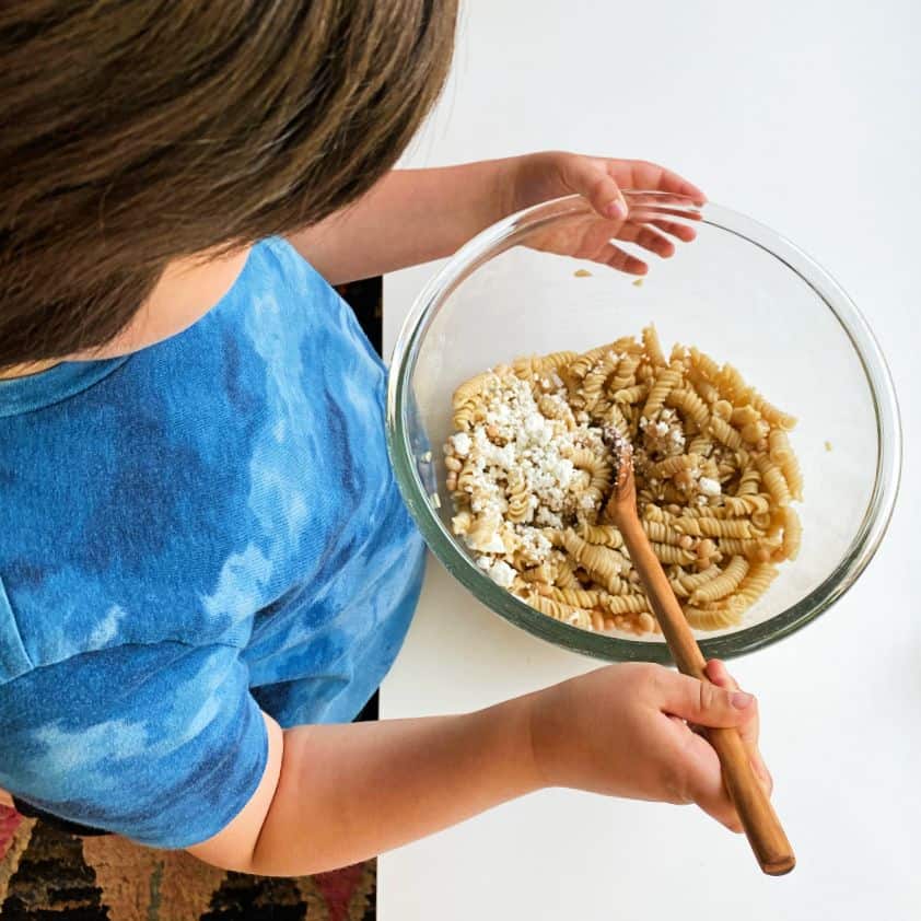 An image of a boy making pasta salad.