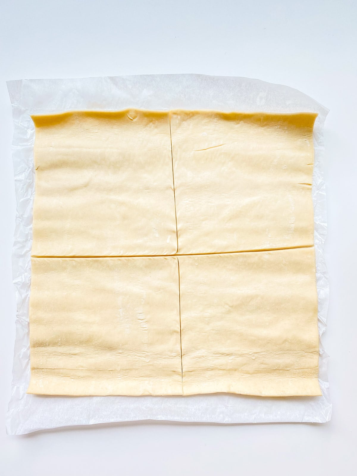 An image of a sheet of puff pastry portioned into 4 squares.