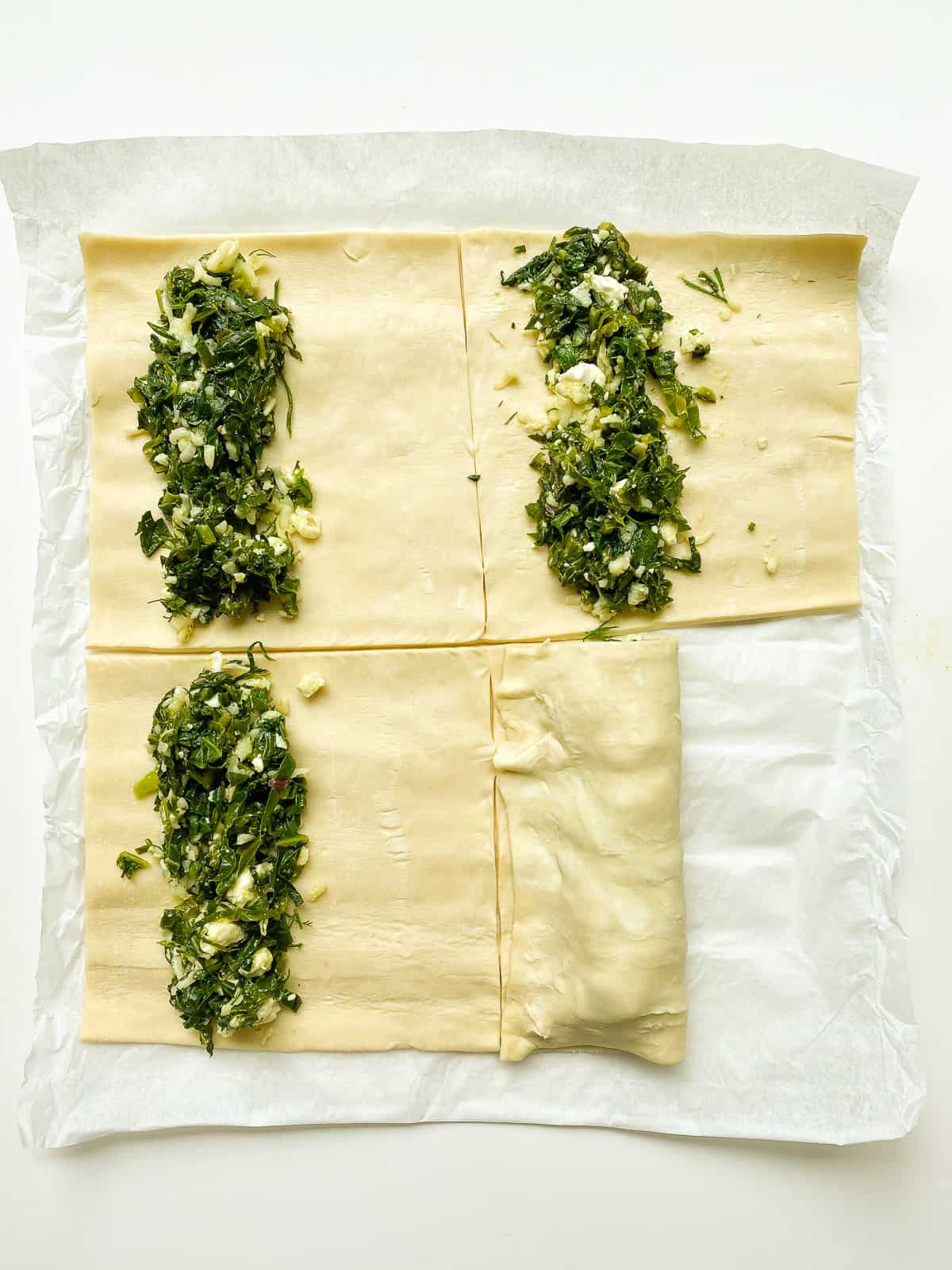 An image of puff pastry rolls being folded and crimped before baking.