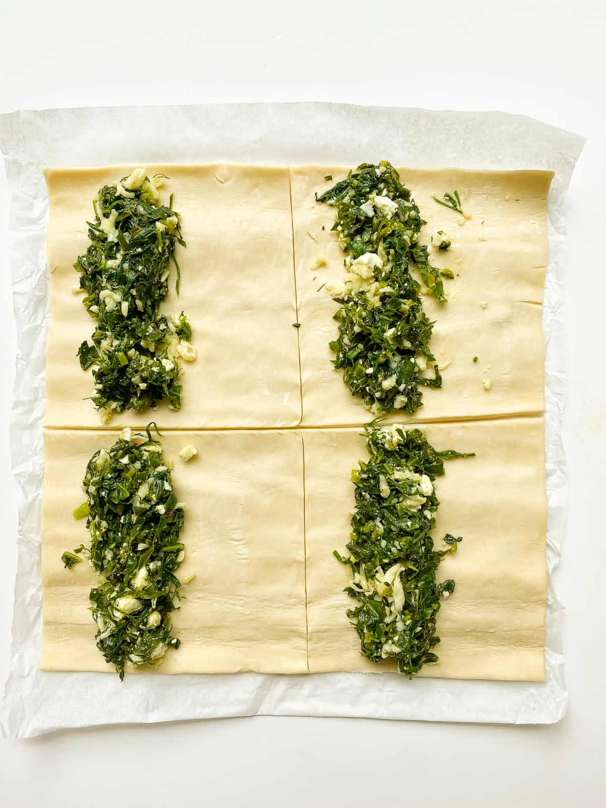 An image of green filling on the portioned pastry, before crimping and baking.