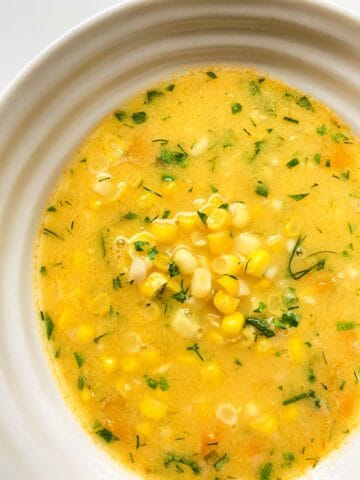 A close up image of Corn Soup with Ginger and Dill in a white ceramic bowl.