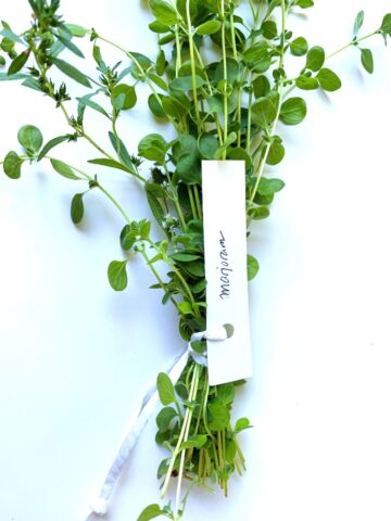 An image of fresh herbs that have been wrapped in a bundle, with a name tag on the bundle.