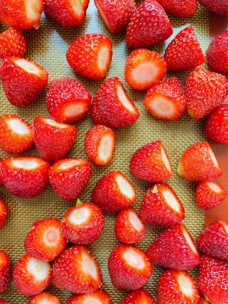 An image of prepared strawberries on a tray ready to be frozen.