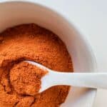 An image of tomato powder in a white ceramic bowl.