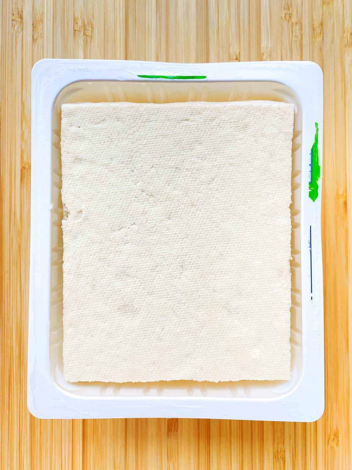 An image of tofu in its plastic packing tray.