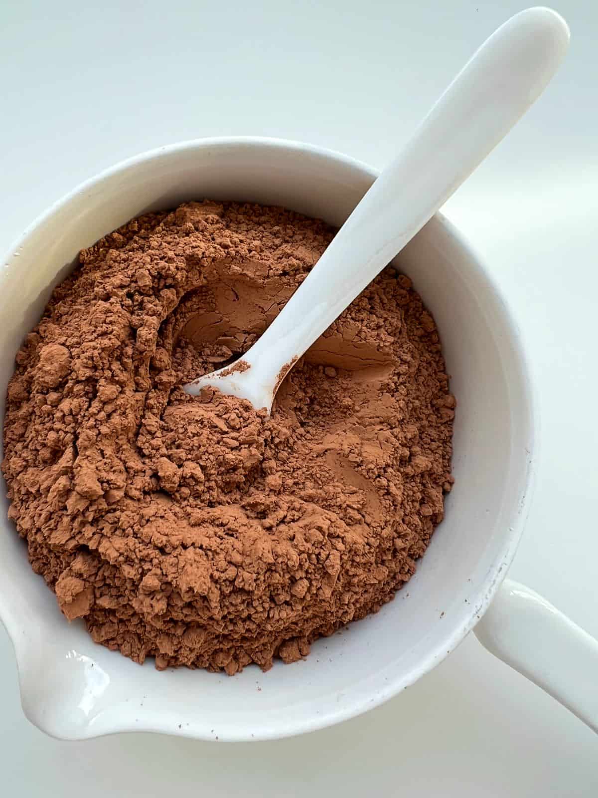 A white ceramic bowl contains cacao powder.