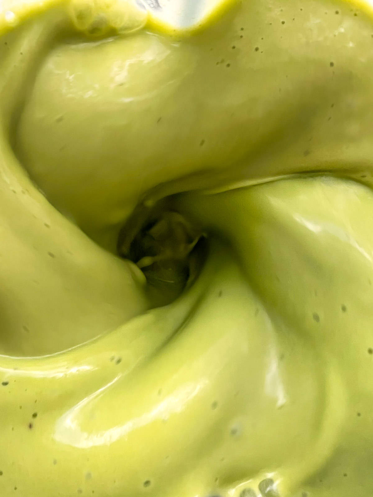 A close up image of a green smoothie in the blender.