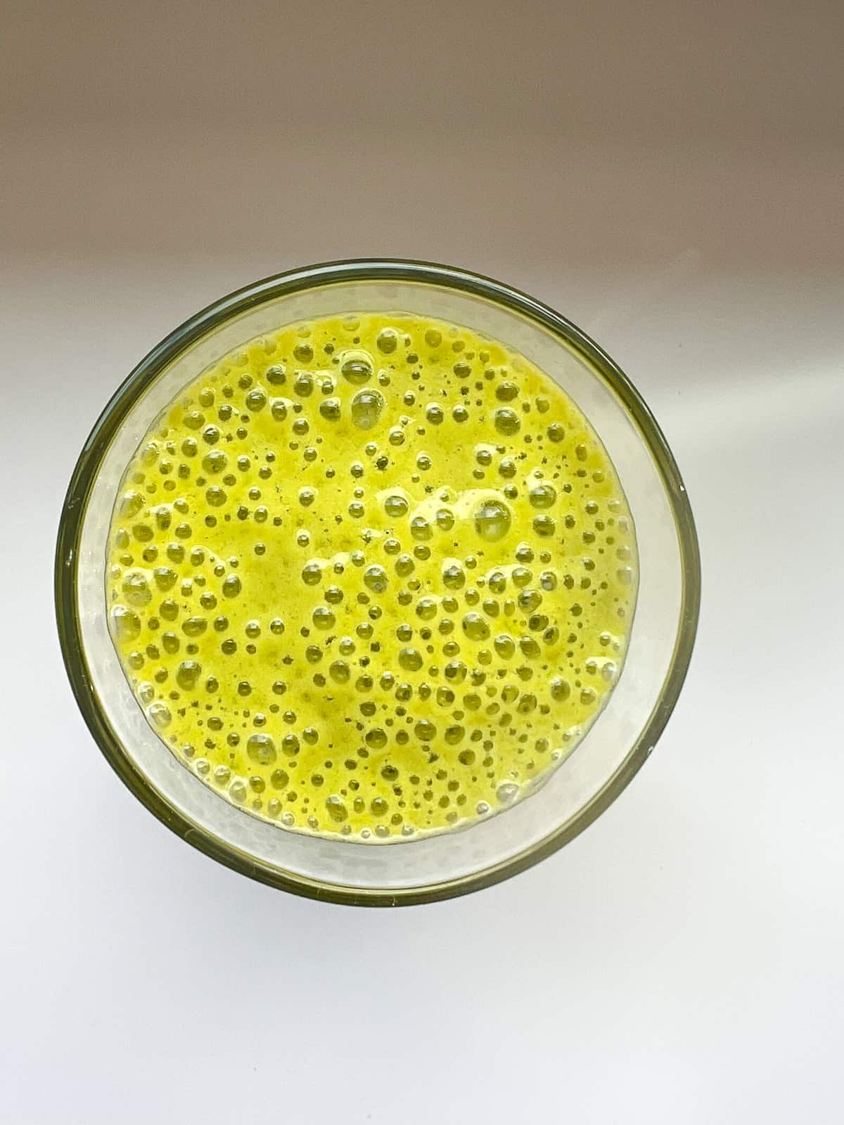 An image of green smoothie in a clear glass.
