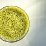 An image of a green smoothie against a white counter top.