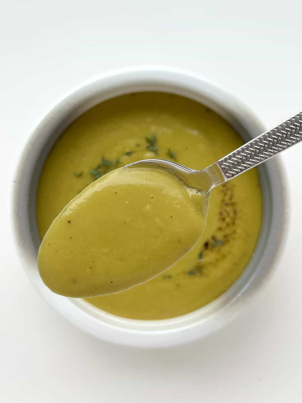 A spoonful of Smoky Herbed Split Pea Soup with the bowl of soup in the background.