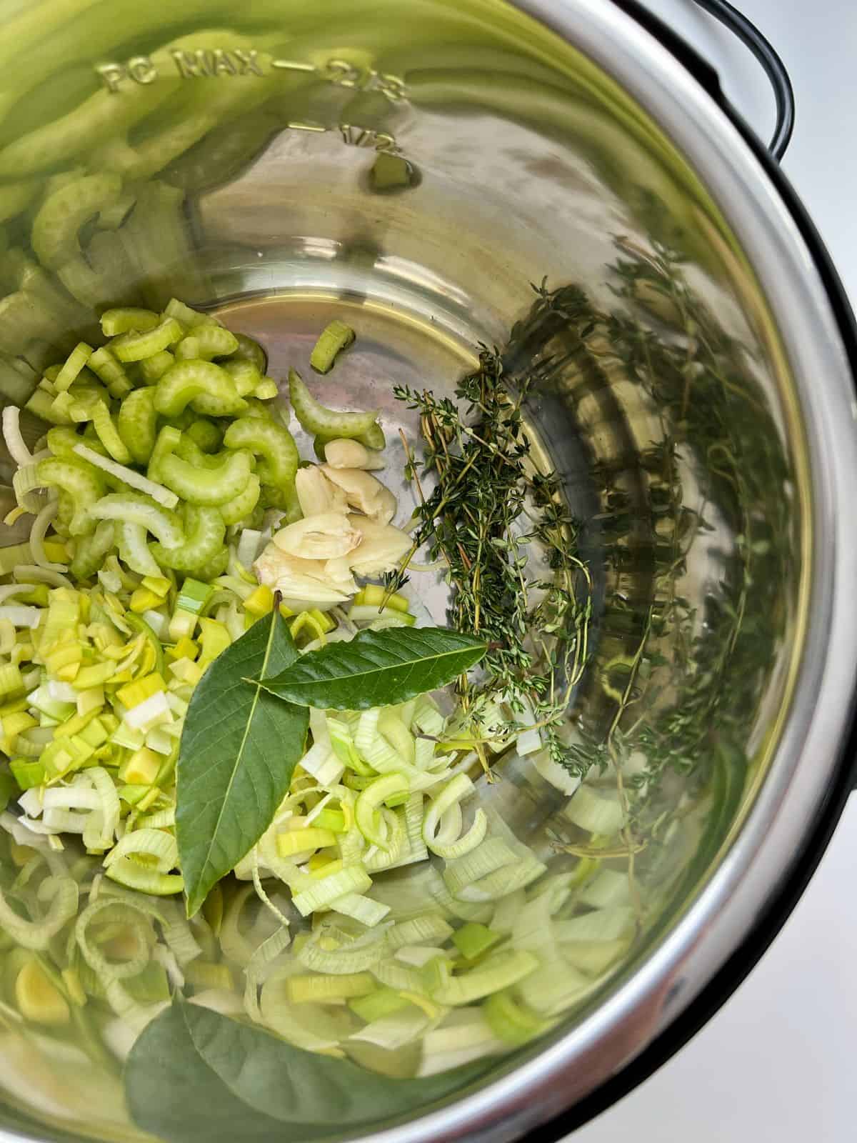 An image of the vegetable ingredients needed for Smoky Herbed Split Pea Soup in the stainless steel inner pot of an Instant Pot.