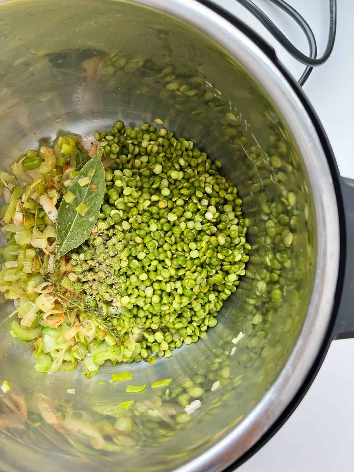 An image of the vegetable ingredients needed for Smoky Herbed Split Pea Soup, with the split peas added in, in the stainless steel inner pot of an Instant Pot.