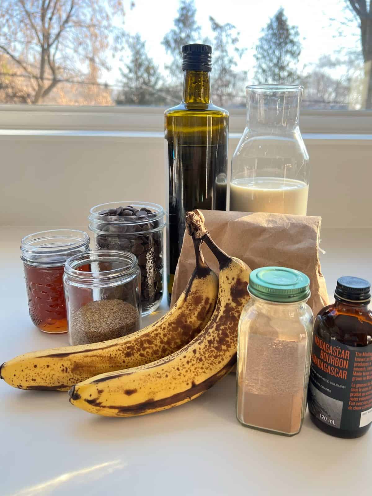 An image of all of the ingredients needed to make Super Chocolatey Banana Bread sitting on a white counter.