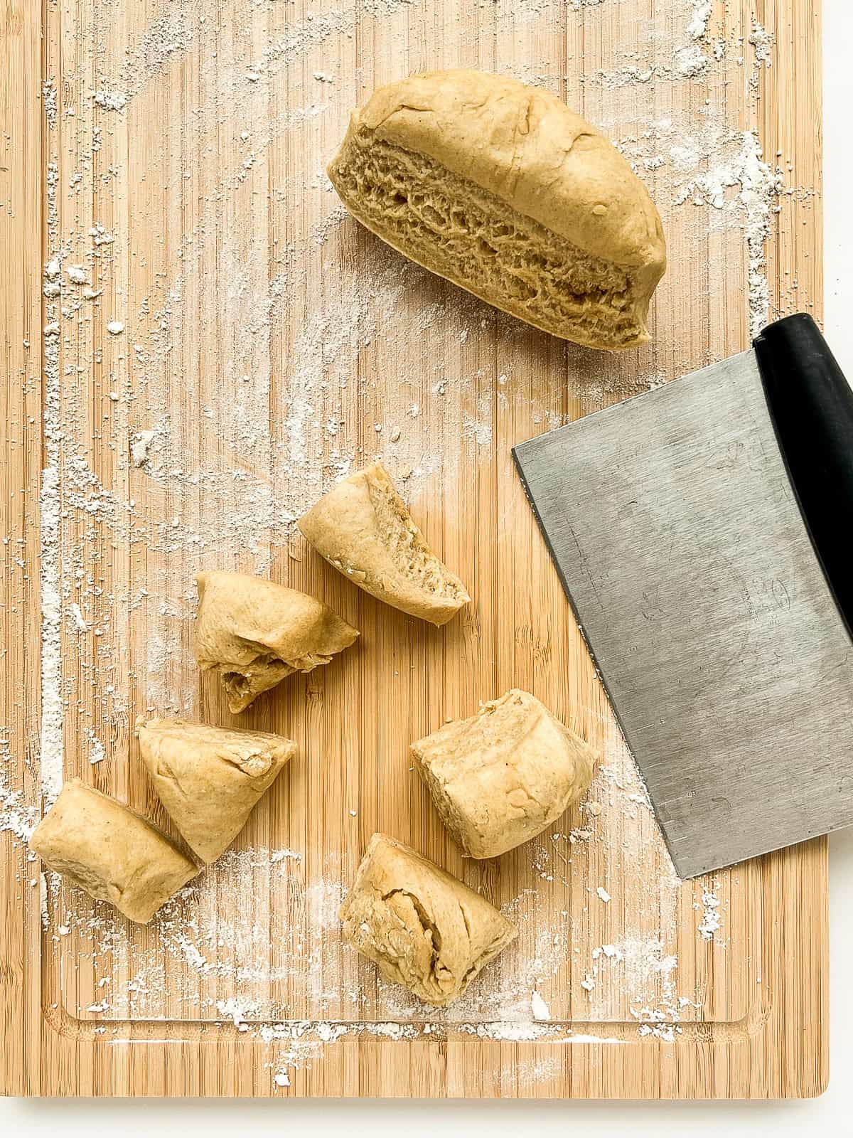 A ball of dough being cut into smaller portions with a dough cutter.