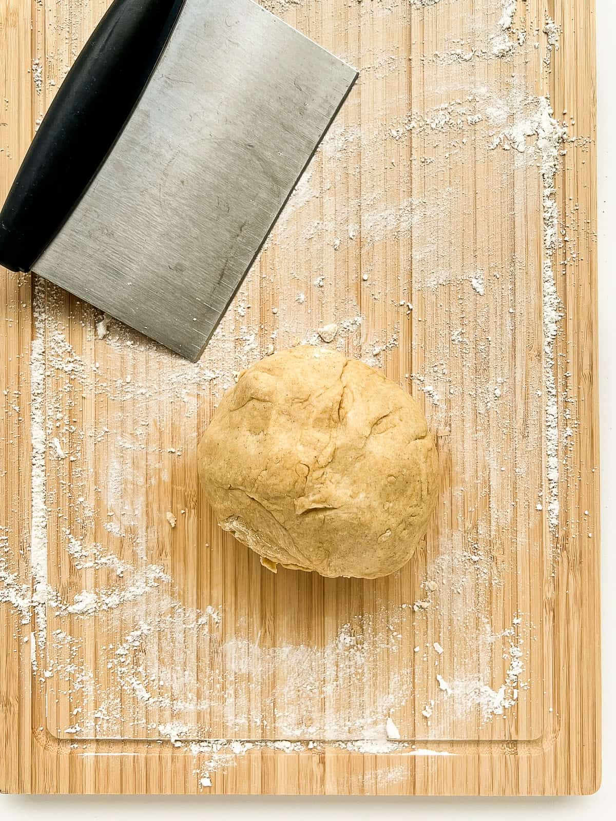 A ball of dough on a floured cutting board.