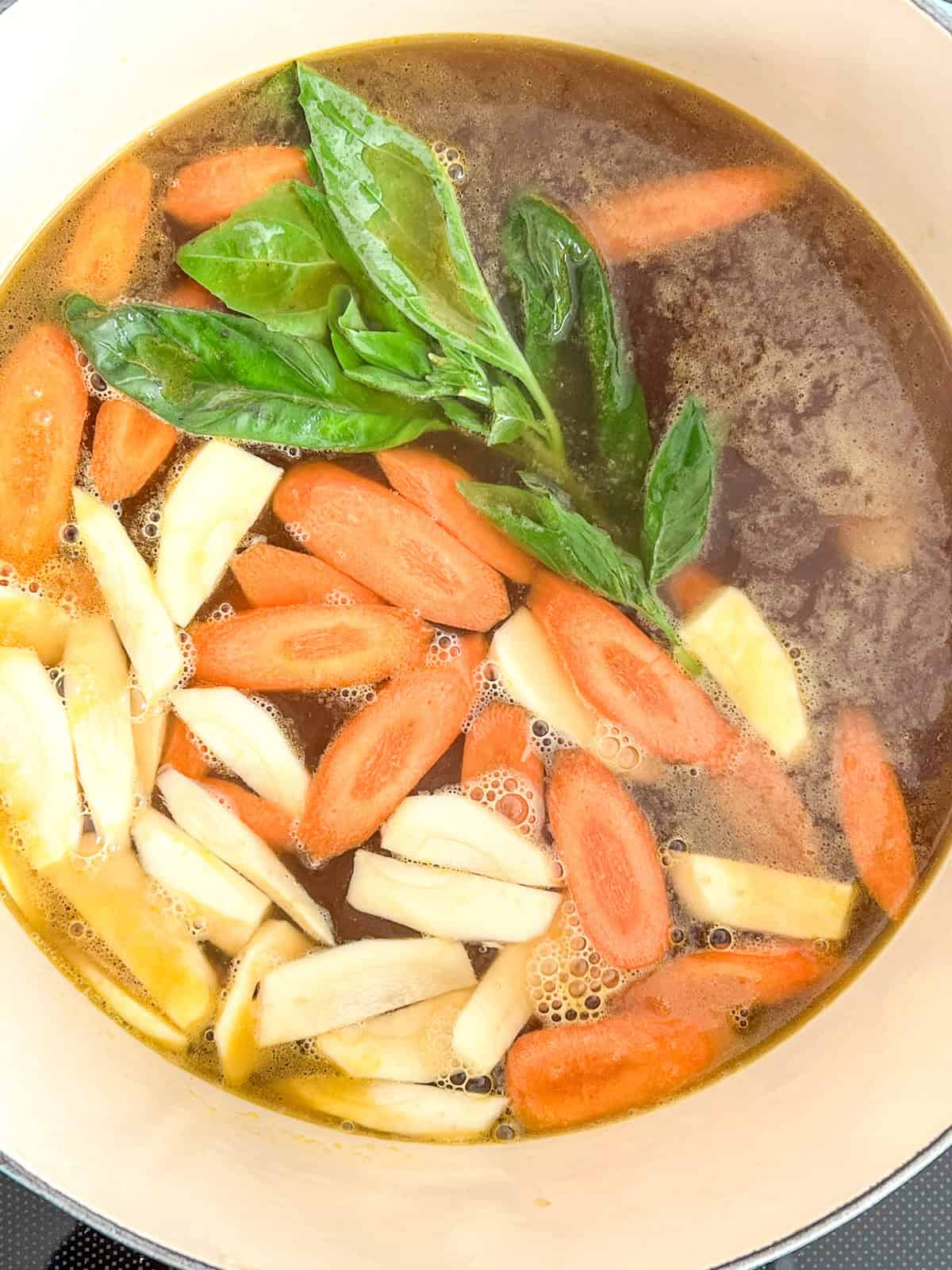 Vegetarian Matzo Ball Soup cooking inside an enamel pot.