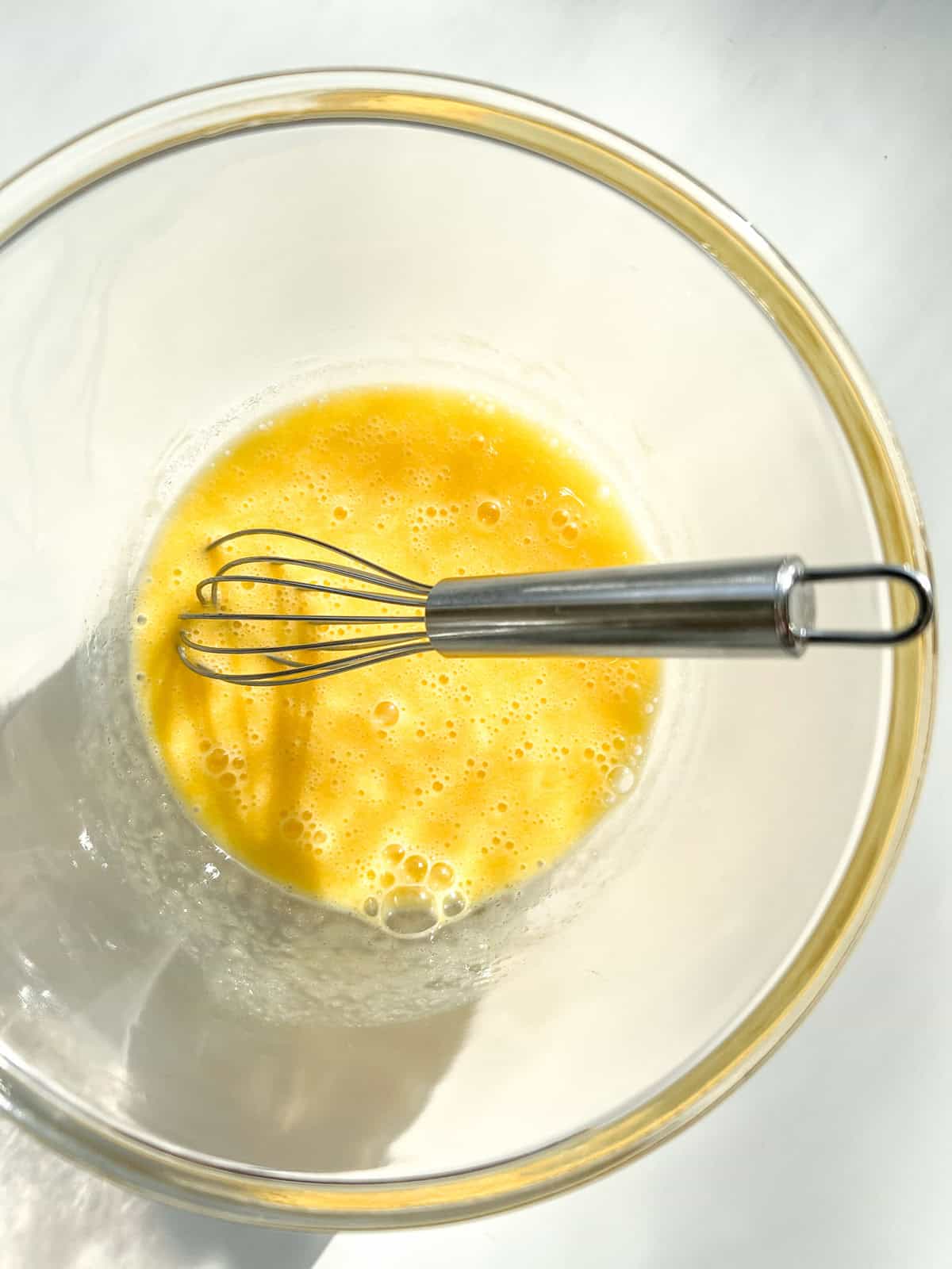 Eggs whisked in a glass bowl as part of the matzo ball making process.