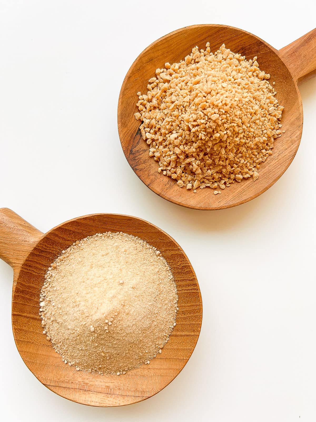 Two wooden bowls containing fine and large granulated maple sugar.