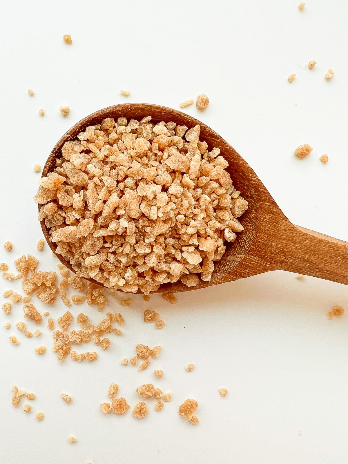 A wooden spoon containing large granule of maple sugar.