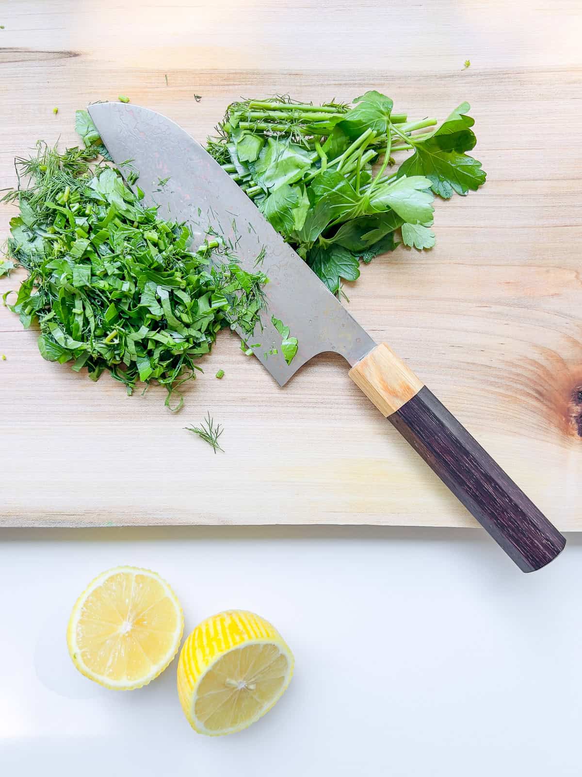 An image of cut herbs on a wooden cutting board.