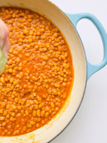 An image of tangy white beans in a white and turquoise enamel pan.