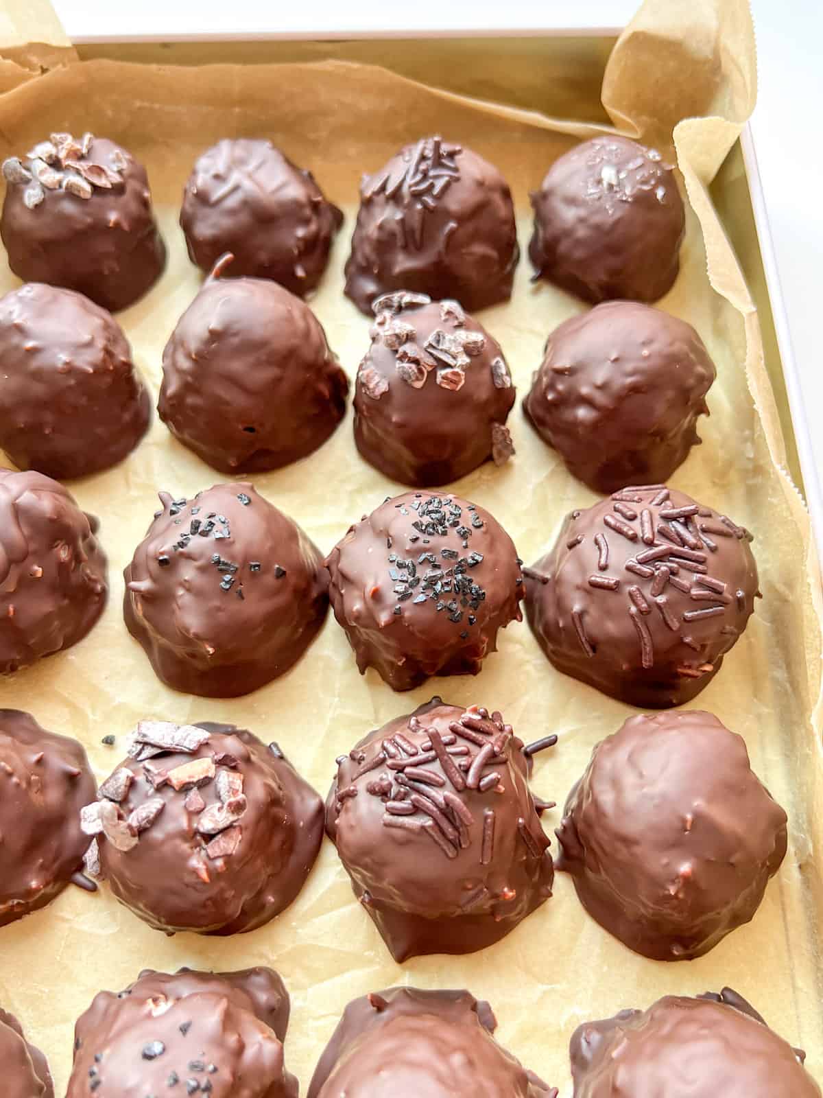An image of Chocolate Coconut Bonbons in a tin lined with parchment paper.