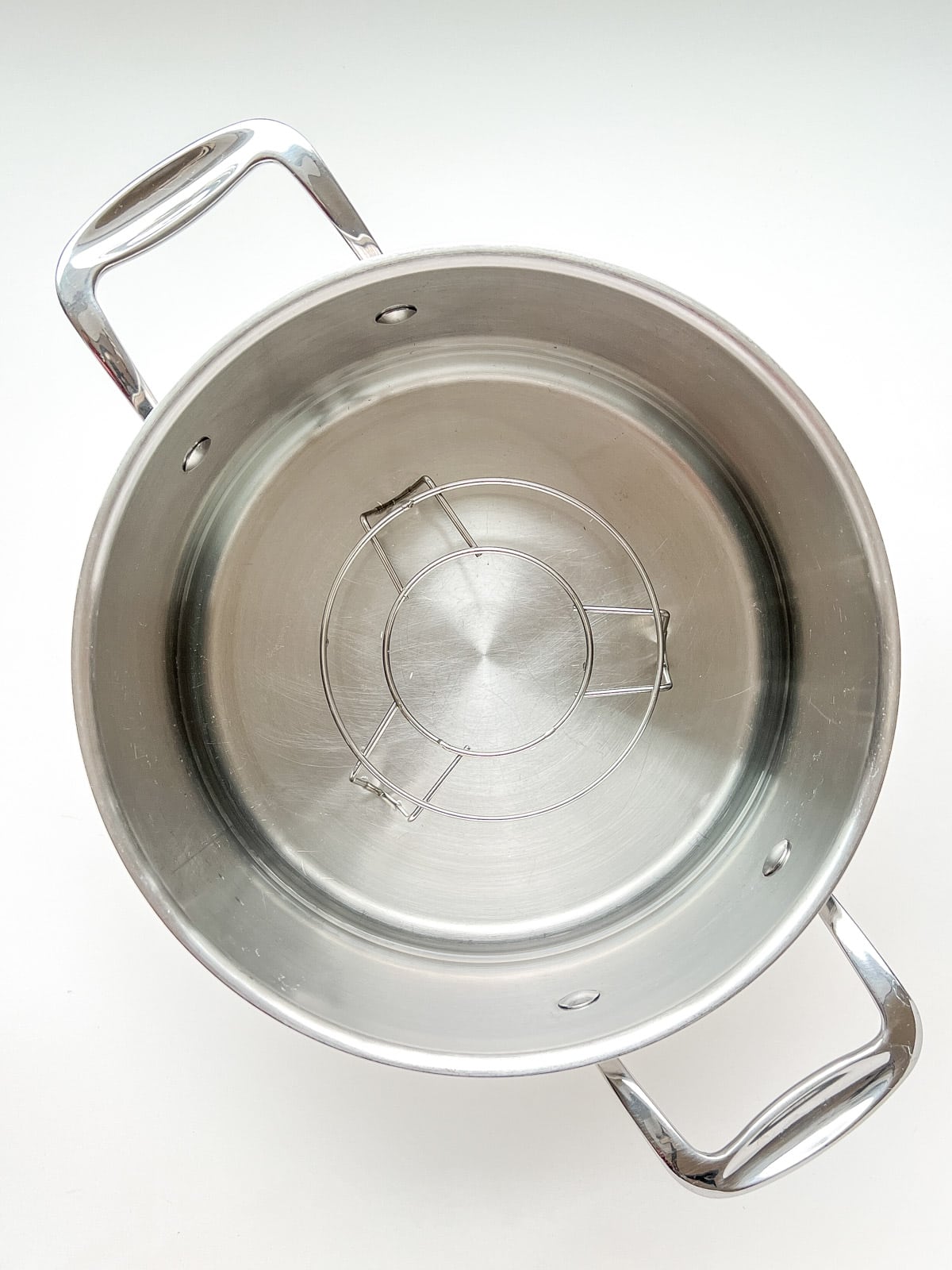 An image of a metal trivet inside a pot to be used as a steamer.