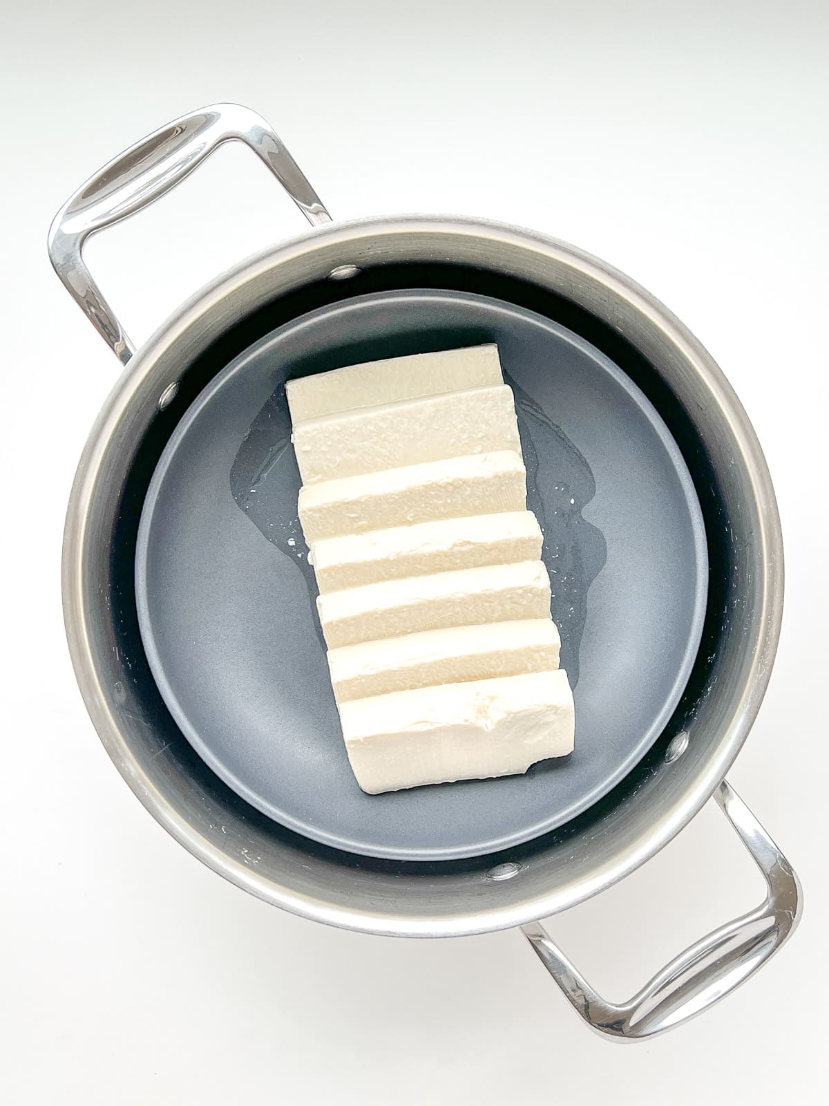 An image of a dish of sliced tofu inside a pot that will be used to steam the tofu.