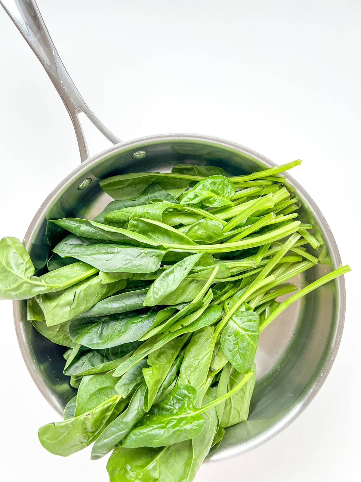 An image of spinach inside a pan before it is cooked.