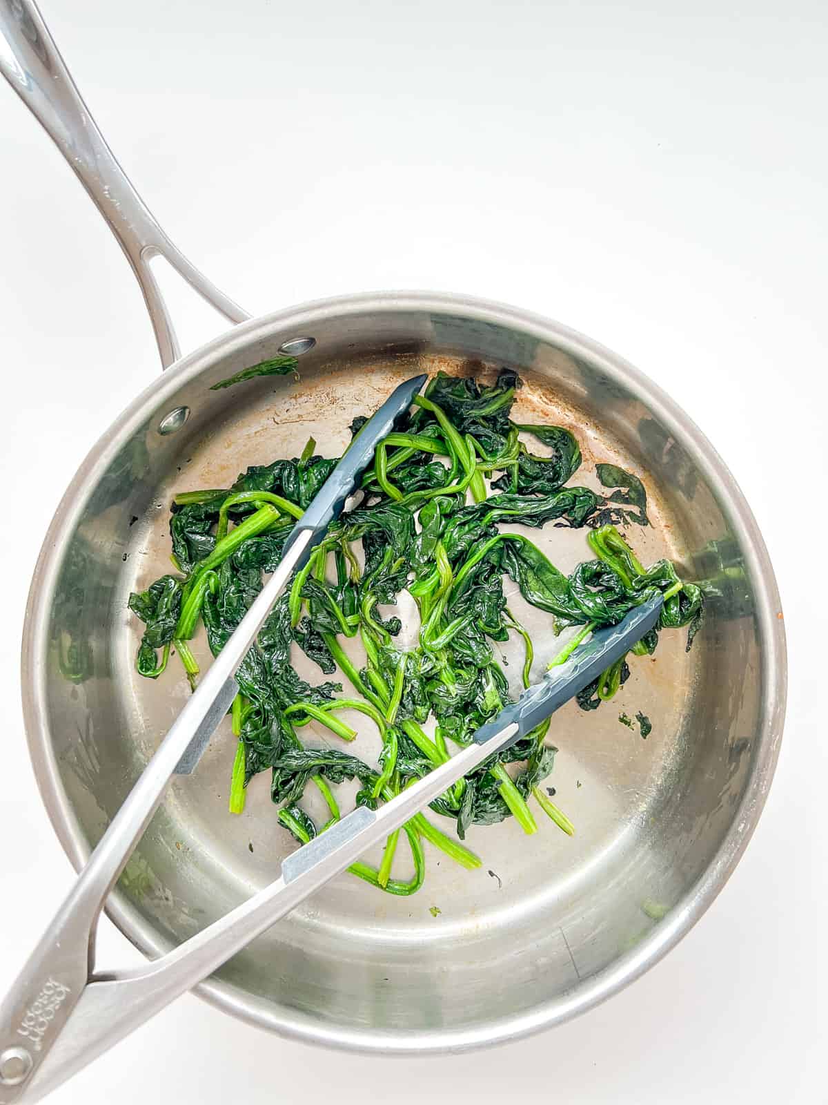 An image of spinach inside a pan after it is cooked.