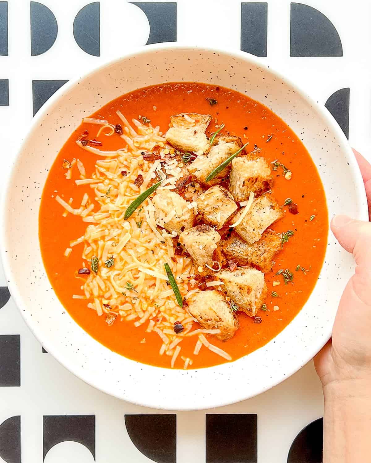 An image of Roasted Tomato and Garlic Soup with Pan-Crisped Croutons ready to eat with a graphic black and white background.