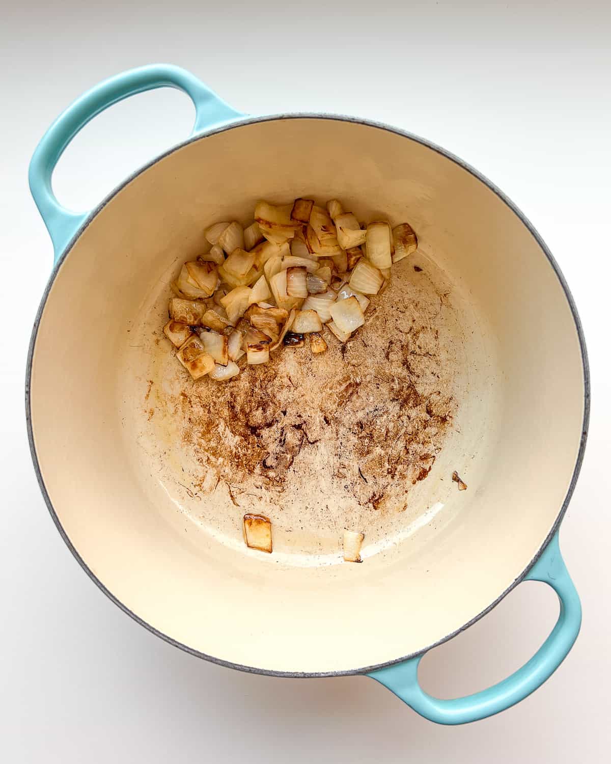 An image of diced onions and olive oil in a soup pot before after being cooked.