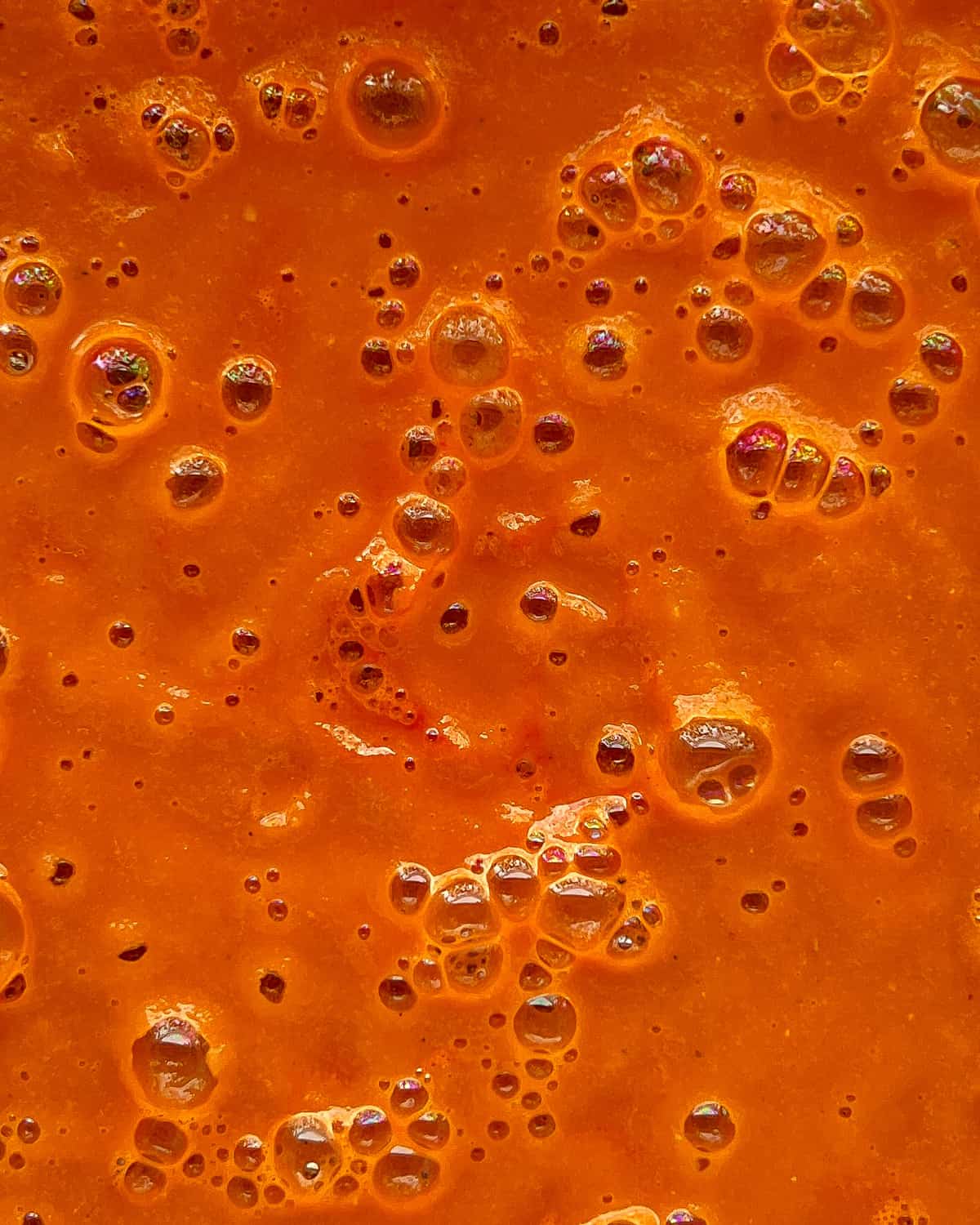 A close up image of roasted tomato soup in a blender cansiter after being blended.