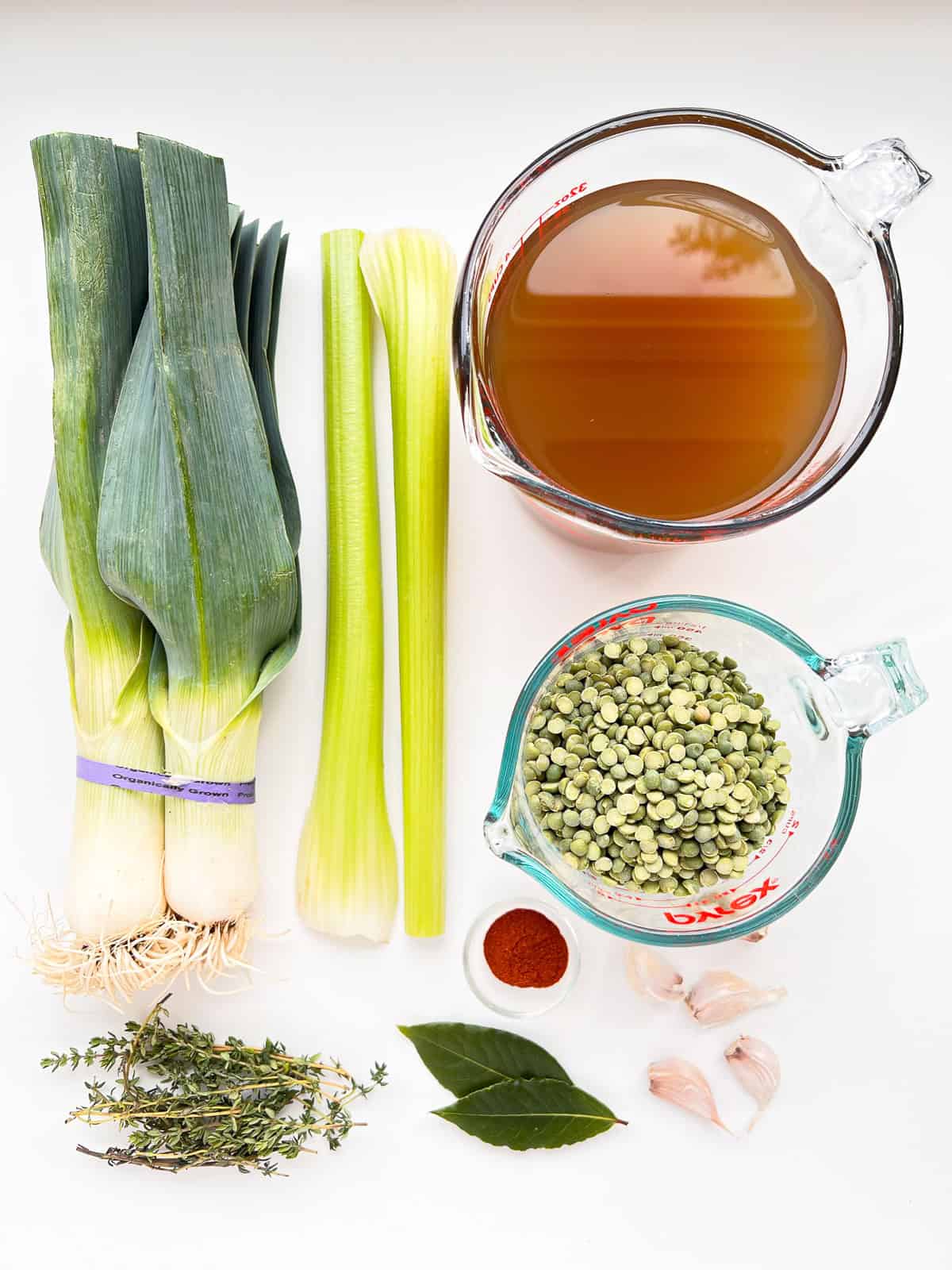 An image of the vegetable ingredients needed for Smoky Herbed Split Pea Soup laid out geometrically on a white countertop.