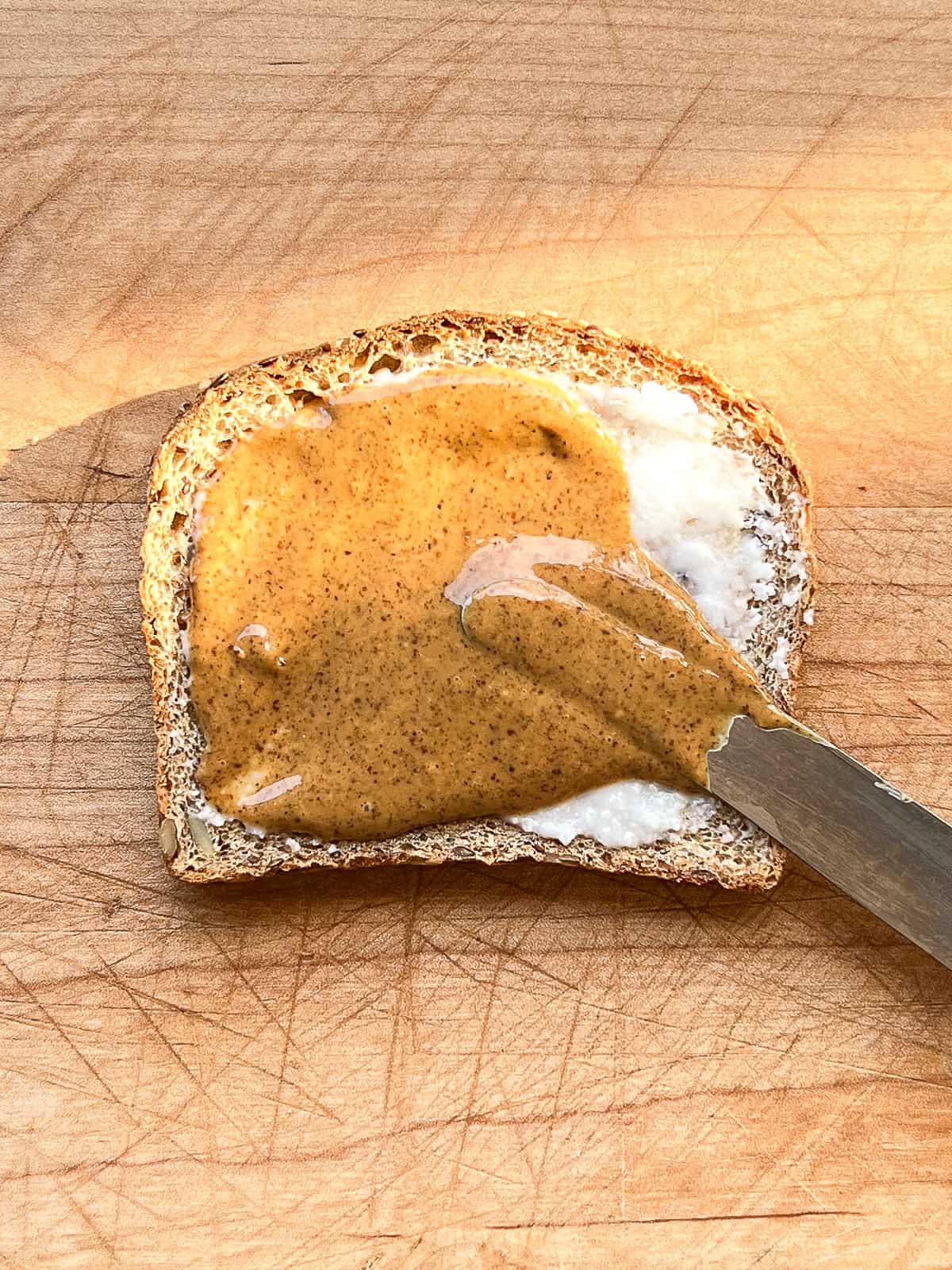 An image of coconut butter and almond butter being spread on toast.