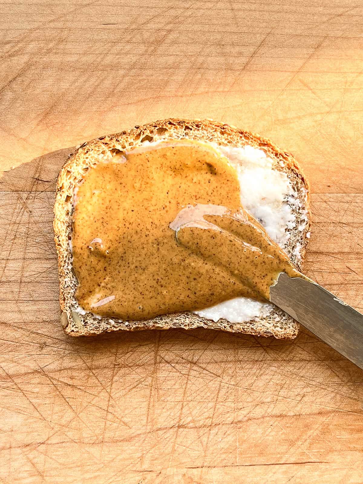 An image of coconut butter and almond butter being spread on toast.