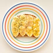 An image of banana supreme toast on a rainbow coloured plate.