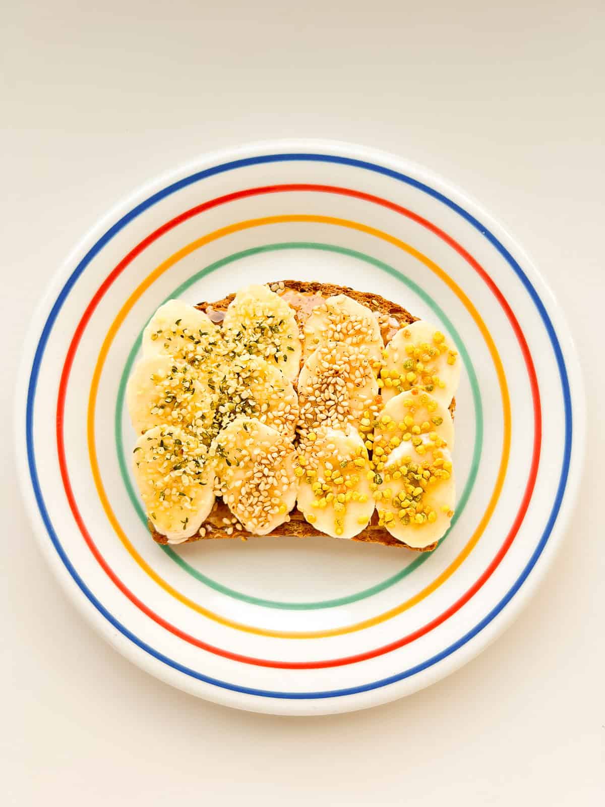 An image of banana supreme toast on a rainbow coloured plate.