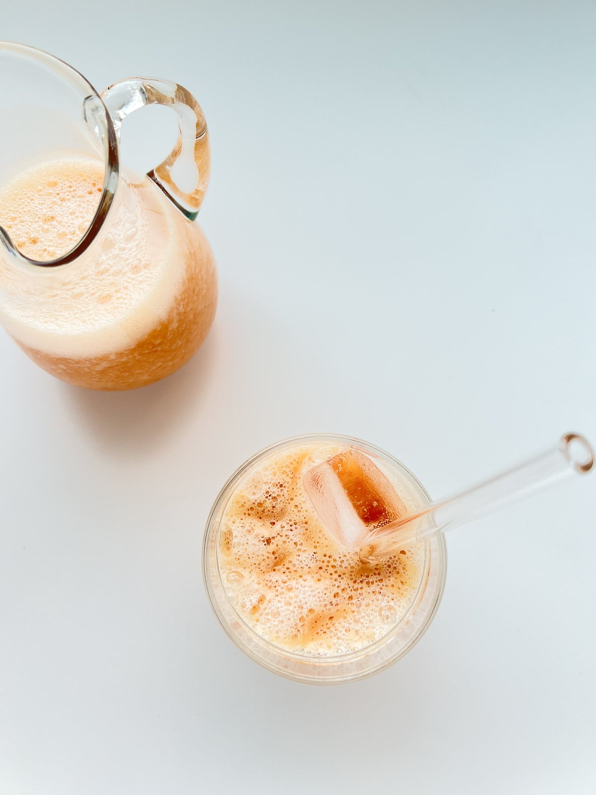 An image of a fruit frappe in a glass with a pitcher full of the same nearby.
