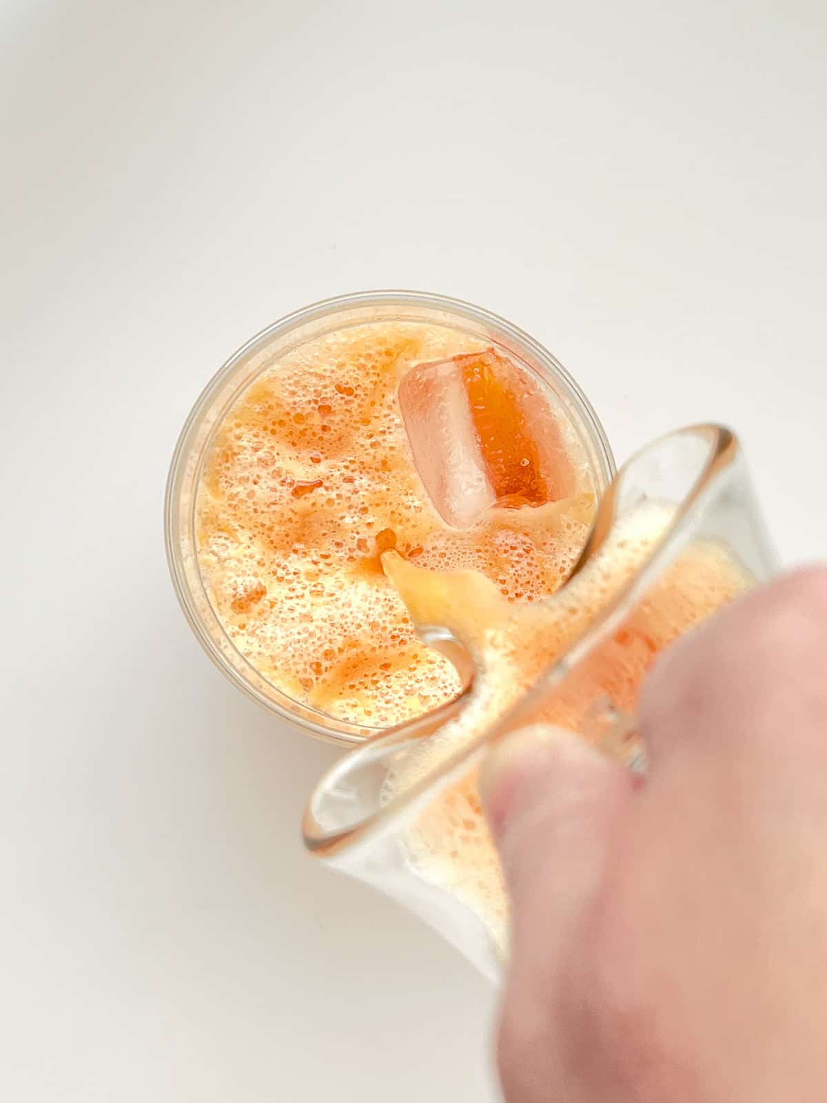 An image of an orange colour drink being poured into a glass.