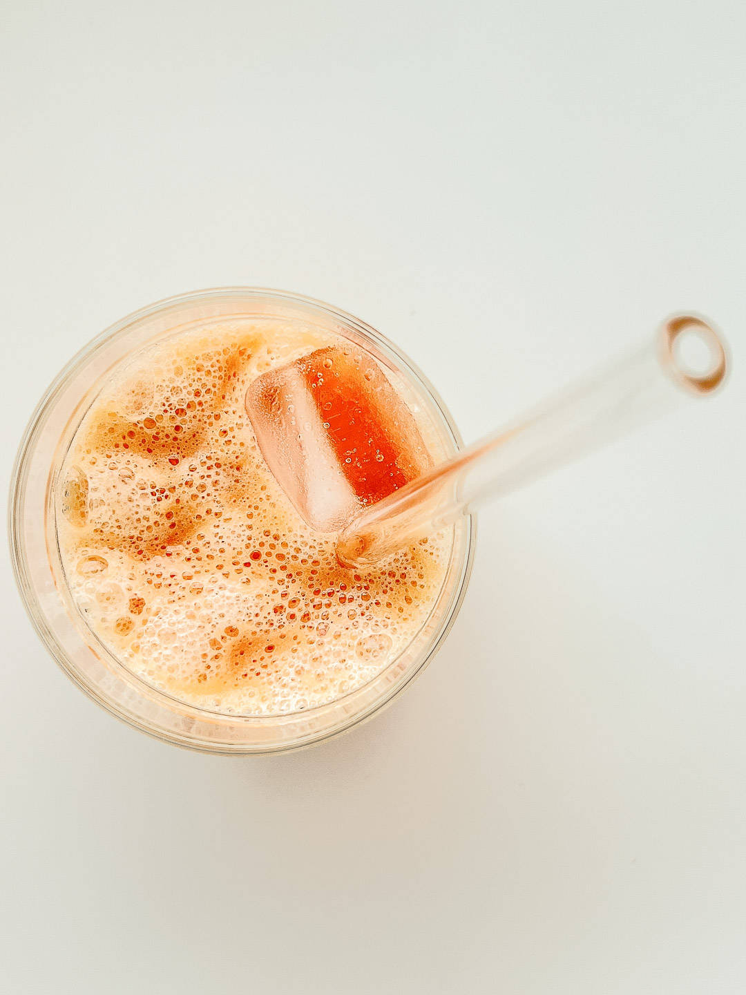 An image of an orange smoothie in a glass with a glass jar.