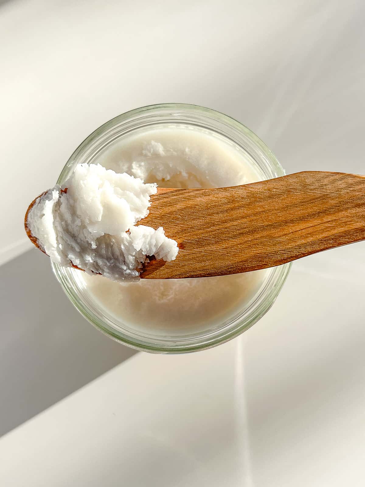 An image of a jar of coconut butter with a wooden spreader on top that has scooped up some of the butter.