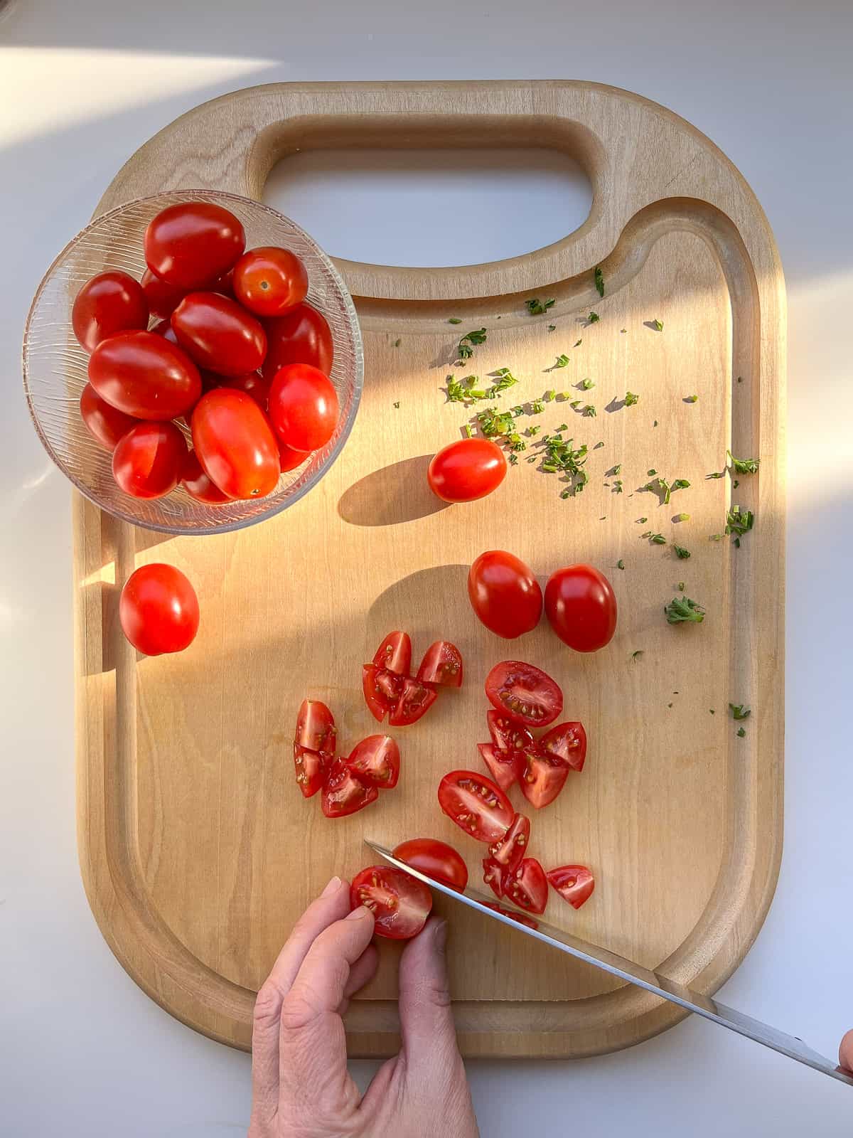 An image of tomatoes being cut on a wooden cutting board.