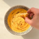 An image of a hand dipping garlic toast into a bowl of lentil soup.
