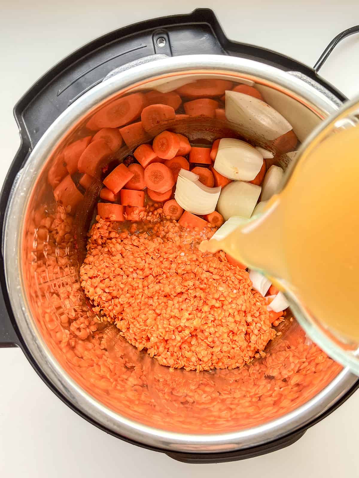 An image of veggie stock being poured into an instant pot.