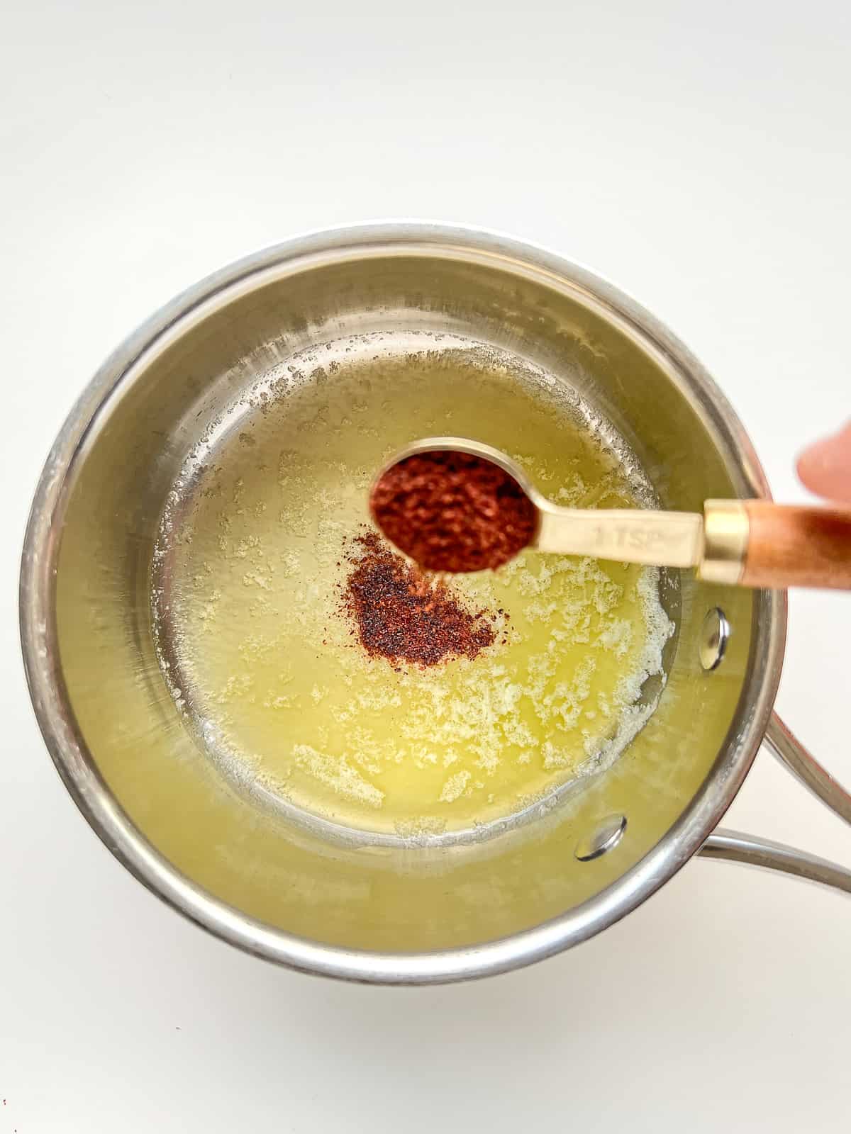 An image of sumac being sprinkled into melted butter.