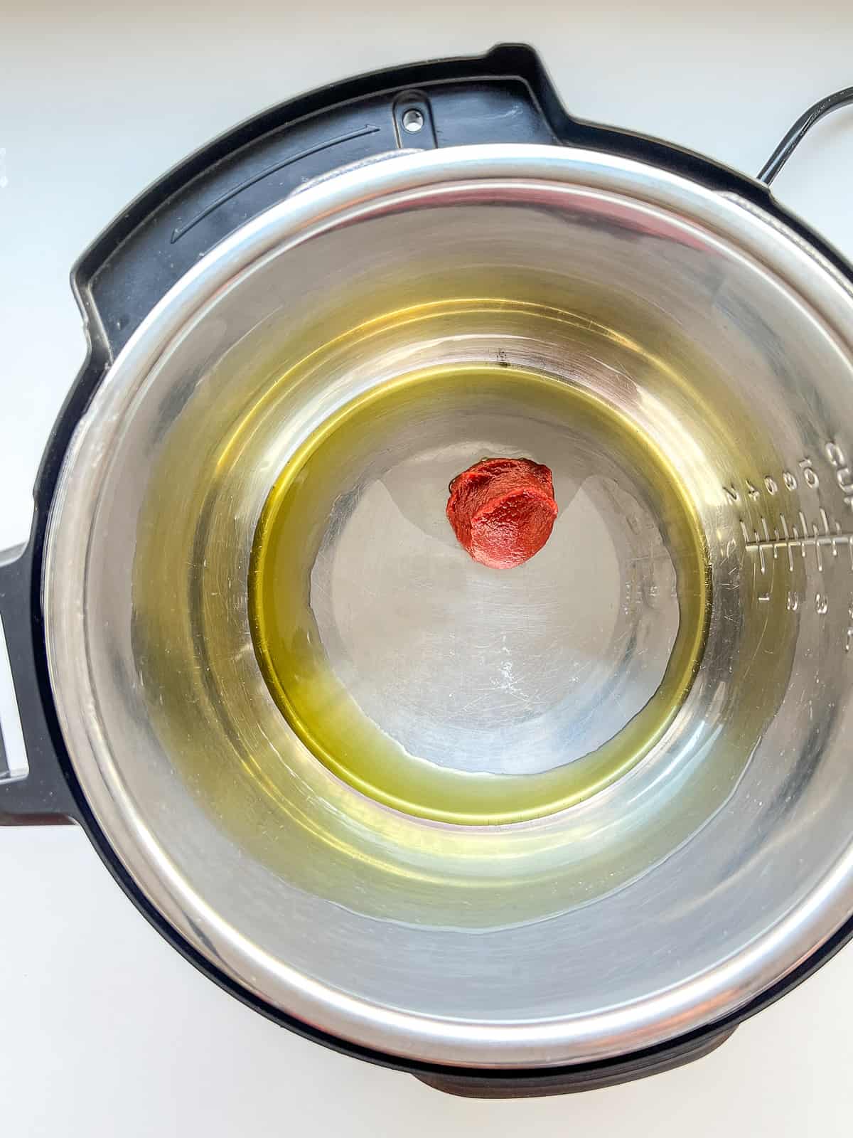 An image of oil and tomato paste in an instant pot.