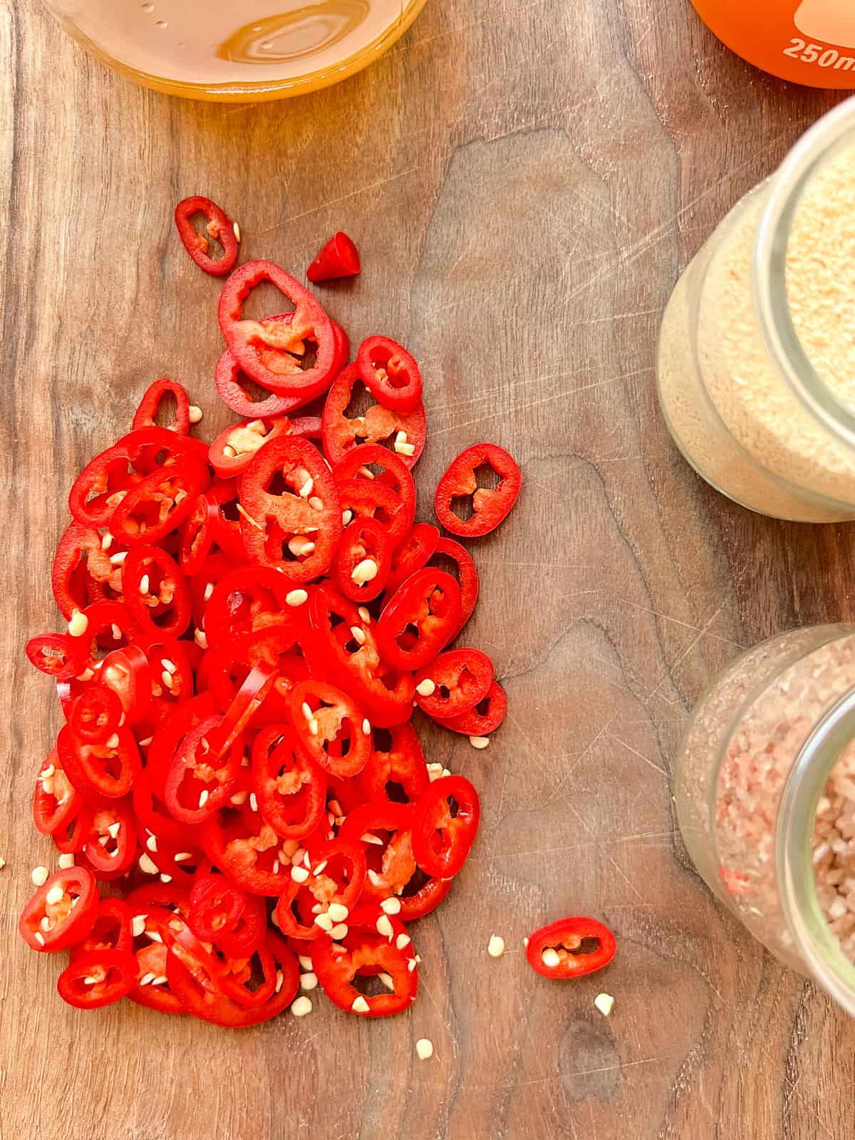 An image of sliced red chillies on a wooden cutting board.