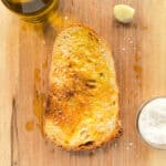 An image of golden garlic toast on a wooden cutting board.