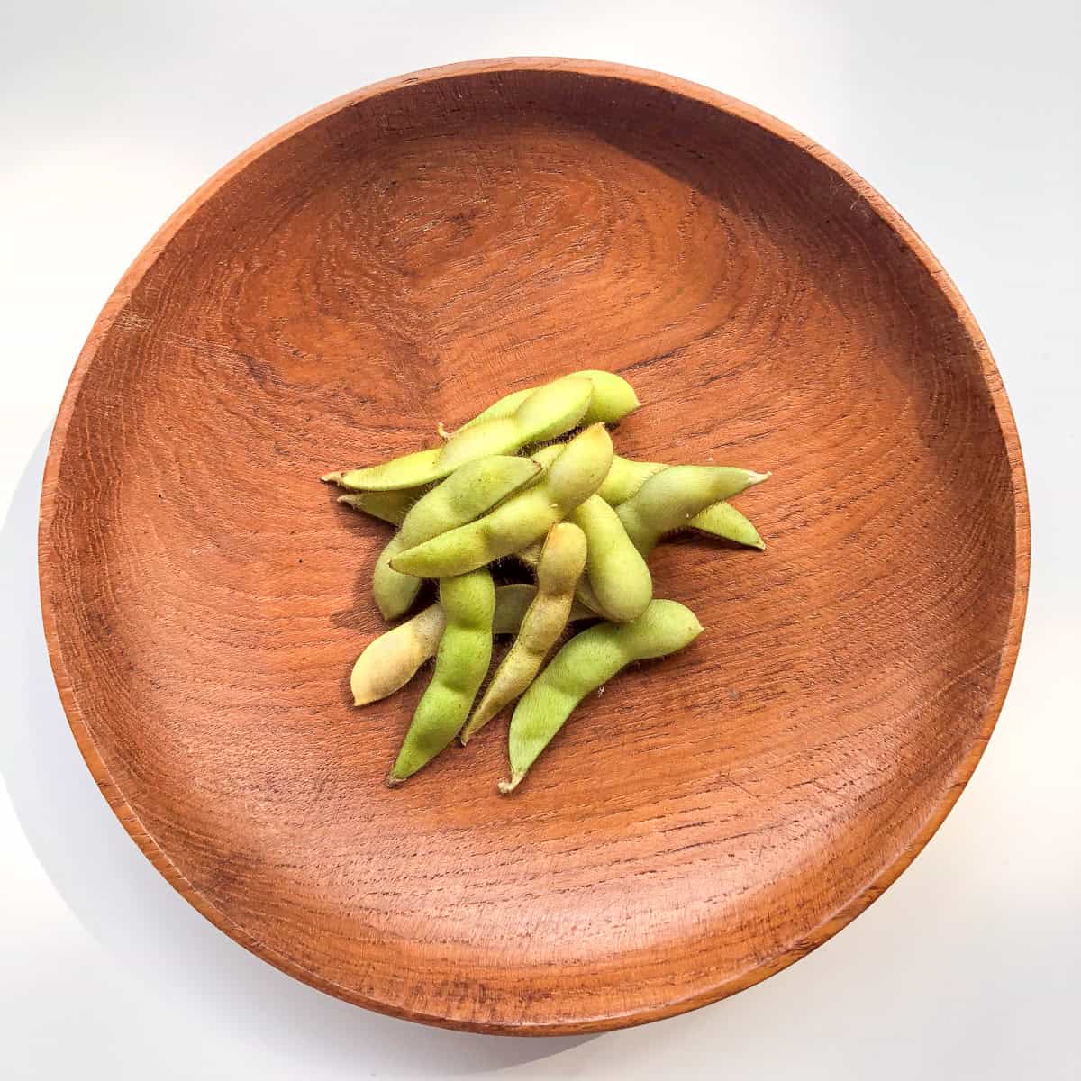 A wooden bowl containing edamame.